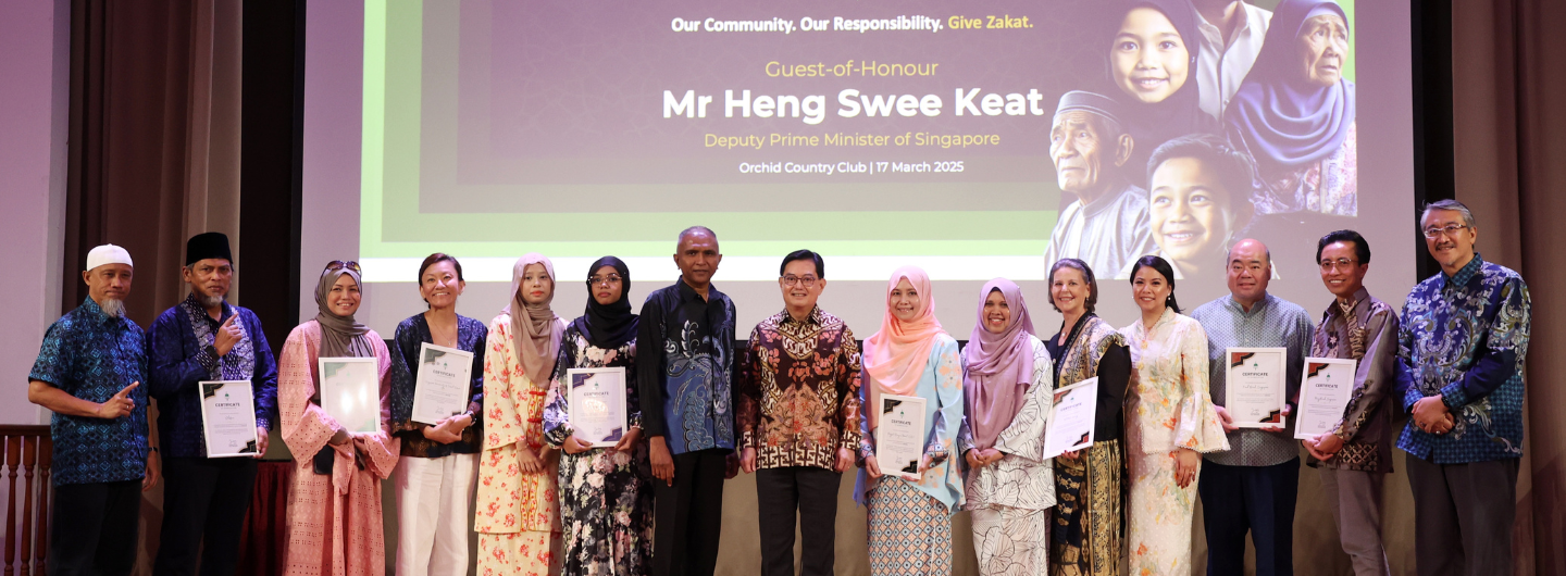 Group poses with certificates below a screen displaying "Mr. Heng Swee Keat."